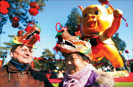 A foreign tourist and a local resident share a light moment at the Ditan Park Temple Fair in Beijing on Tuesday. [Photo: Chen Xiaogen /China Daily]