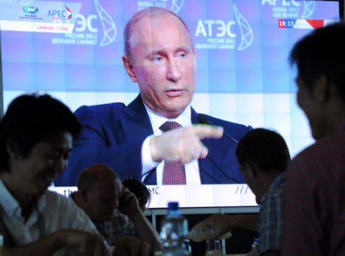 Journalists watch Russian President Vladimir Putin on a screen delivering his speech on the eve of the Asia-Pacific Economic Cooperation forum in Vladivostok on Friday. [Photo/Agencies]
