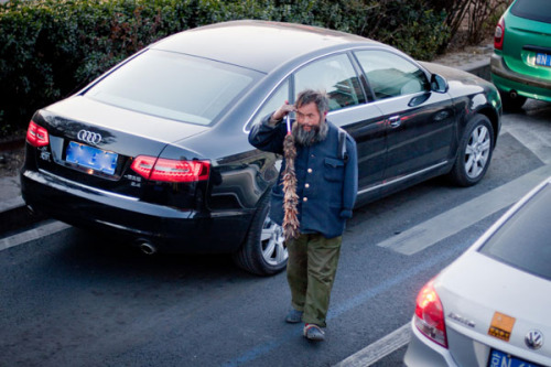 A beggar, with a feather duster in hand, loiters among heavy traffic in Beijing, offering cleaning services in exchange for money. China's miraculous economic growth in past decades has left an increasing number of people behind financially. Mao Yanzhen
