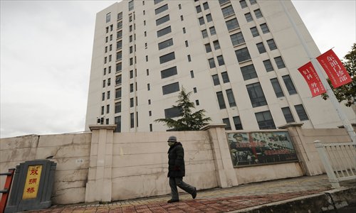 A person walks past a 12-story building alleged in a report on Tuesday by the Internet security firm Mandiant to be the home of a Chinese military-led hacking group in Shanghai's northern suburb of Gaoqiao. Photo: AFP 
