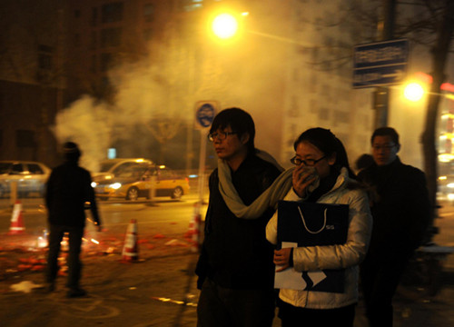 A woman covers her face with a scarf while people set off fireworks in Beijing, on the traditional Chinese Lantern Festival, Feb 24, 2013. [Photo/Xinhua]