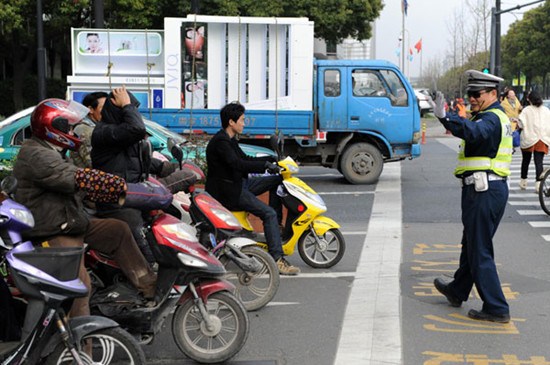A policeman directs motor vehicles to stop before the crossing line in Hangzhou city, Zhejiang province on March 21. [Photo/Xinhua]
