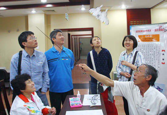Kong Lingmin (right) shows his traditional kite craftsman skills at a job fair on Sunday, the annual National Day for Helping the Disabled. The job fair is aimed at providing more employment opportunities for disabled people and preserving folk art. ZOU HONG / CHINA DAILY