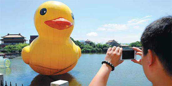 A visitor to Hengdian World Studios in Dongyang, Zhejiang province, takes photos of an inflatable rubber duck. [Photoby Bao Kangxuan/China Daily]