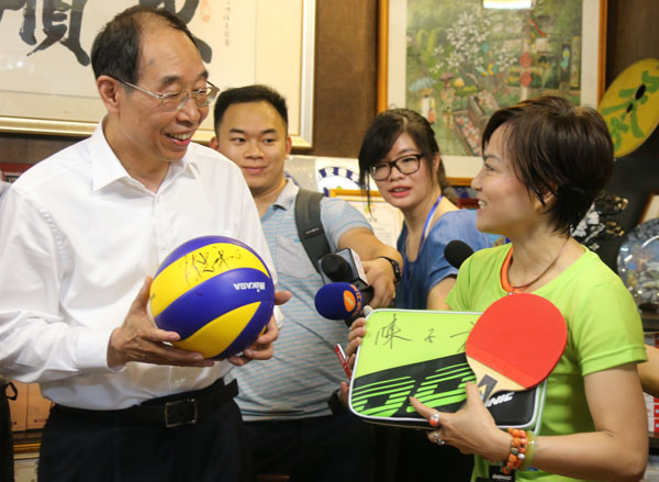 You Quan (left), top leader of Fujian province, gives a volleyball signed by Chen Zhonghe, former head coach of China women's volleyball team, and a table-tennis paddle to a resident of Taipei's Zhongshun neighborhood during a visit on Thursday. Hu Meidong / China Daily