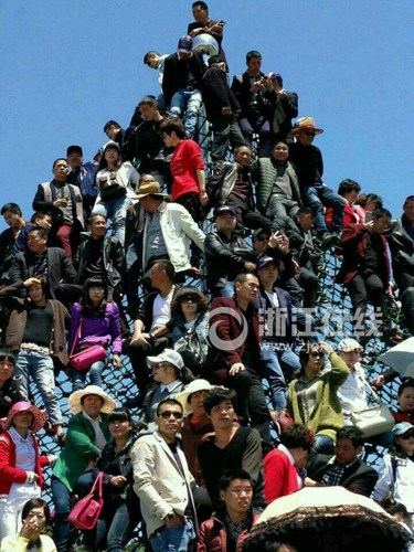 Dozens of tourists climb onto a climbing net on a wire frame to get a better view of a traditional performance celebrating a flower gala, April 14, 2015. (Photo/www.zjol.com.cn) Dozens of tourists climb onto a climbing net on a wire frame to get a better view of a traditional performance celebrating a flower gala, April 14, 2015. (Photo/www.zjol.com.cn)