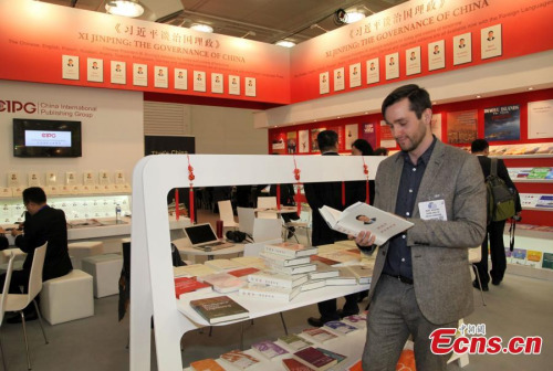 A visitor reads Xi Jinping: The Governance of China at the London Book Fair in London, April 14, 2015. (Photo: China News Service/Zhou Zhaojun)