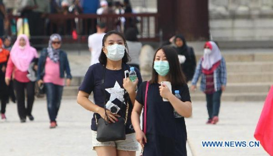 Tourists walk with masks at the Gyeongbokgung Palace in Seoul, South Korea, June 8, 2015. (Photo: Xinhua/Yao Qilin) 
