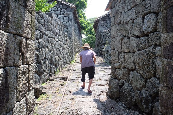 An old woman walks in an alley paved with lava stones in Sanqing village in Haikou, South China's Hainan province, on June 9, 2015. (Photo by Huang Yiming/China Daily) An old woman walks in an alley paved with lava stones in Sanqing village in Haikou, South China's Hainan province, on June 9, 2015. (Photo by Huang Yiming/China Daily)