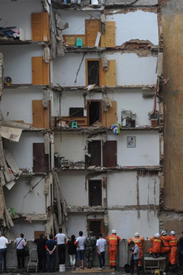 Rescue workers survey the scene after an apartment building collapsed in Zunyi, Guizhou province, on Sunday, leaving two people dead and one missing. A section of the nine-story building in Yan'an Road, Honghuagang district, fell down just before 6 am, officials said. (Photo: Xinhua/Ou Dongqu)
