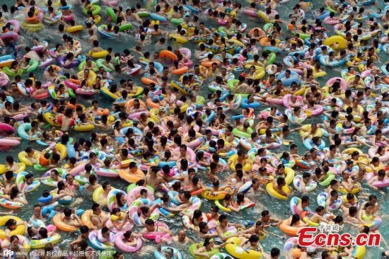Tourists flock to a water resort at Dead Sea in Daying county, Suining city, Southwest China's Sichuan province, July 11, 2015. More than 8,000 people squashed into the 30,000-square-meter pool as temperatures reached 35 degrees Celsius. Chinese netizens joked the crowded scene looked like boiling dumplings. (Photo/CFP)