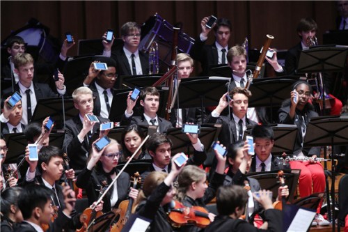 Members of the NYO-USA use their cellphones to create music while performing Tan Dun's Passacaglia: Secret of Wind and Birds. (Photo provided to China Daily) Members of the NYO-USA use their cellphones to create music while performing Tan Dun's Passacaglia: Secret of Wind and Birds. (Photo provided to China Daily)