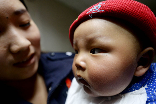 A policewoman attends to a boy in Xinxiang, Henan province, after he was rescued in March from a child trafficking gang. (Photo/China Daily)