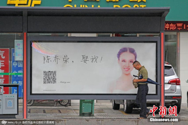 People walk past a marry me LED advertisement which has been installed at a bus station in Xiangyang, Central China's Hubei province, Aug 18, 2015. (Photo/CFP) People walk past a marry me LED advertisement which has been installed at a bus station in Xiangyang, Central China's Hubei province, Aug 18, 2015. (Photo/CFP)
