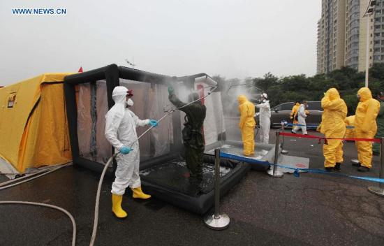 Rescuers are sterilized after cleanup work at the core blast area in Tianjin, north China, Aug. 19, 2015. Cleanup operations of remaining chemicals continued in Tianjin, almost a week after two massive explosions tore through a warehouse storing hazardous goods. (Photo: Xinhua/Wang Haobo)