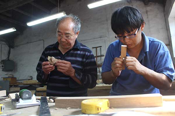 Huang Yongfang (left) checks components of a wooden model.(Photo by Wang Kaihao/China Daily) Huang Yongfang (left) checks components of a wooden model.(Photo by Wang Kaihao/China Daily)