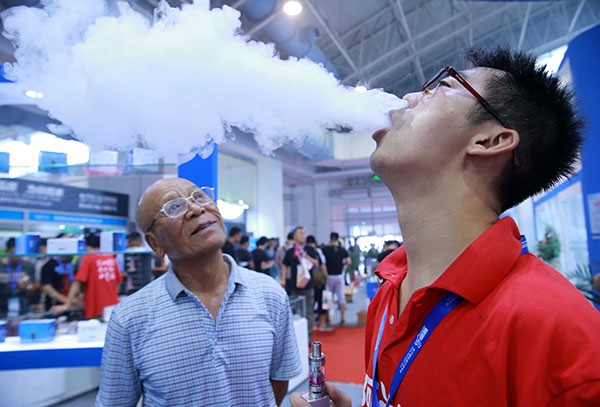 A visitor watches an assistant demonstrate cloud chasing at an e-cigarette exhibition in Beijing in July. (Photo: China Daily/Xiao Chen) A visitor watches an assistant demonstrate cloud chasing at an e-cigarette exhibition in Beijing in July. (Photo: China Daily/Xiao Chen)