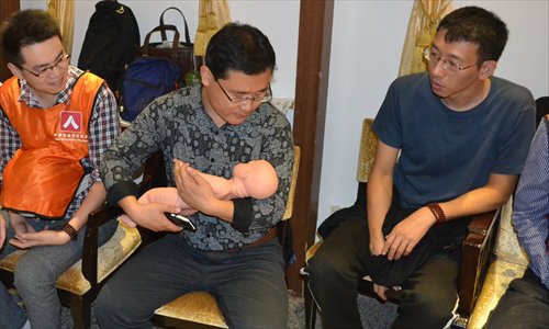 A man learns how to cuddle a baby at the men's morals class in Beijing. (Photo/Courtesy of Fang Gang) A man learns how to cuddle a baby at the men's morals class in Beijing. (Photo/Courtesy of Fang Gang)