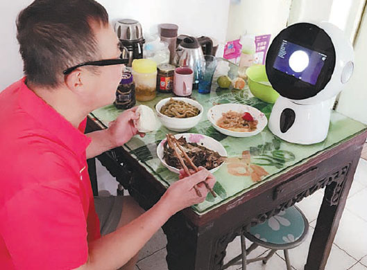 Chi Yunchang, a 60-year-old Shanghai resident, eats a meal while talking to Roby Mini, a robot tailor-made for the elderly market. Provided to China Daily Chi Yunchang, a 60-year-old Shanghai resident, eats a meal while talking to Roby Mini, a robot tailor-made for the elderly market. Provided to China Daily