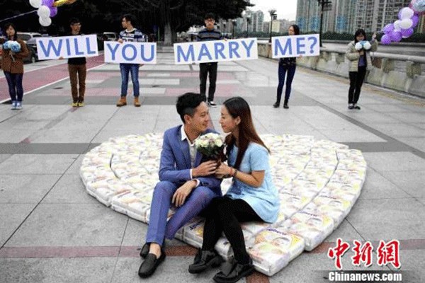 Feng and his girlfriend sit on over 50 bags of diapers along the Pearl River in Guangzhou, South China's Guangdong province, on Nov 1, 2015. [Photo/Agencies]