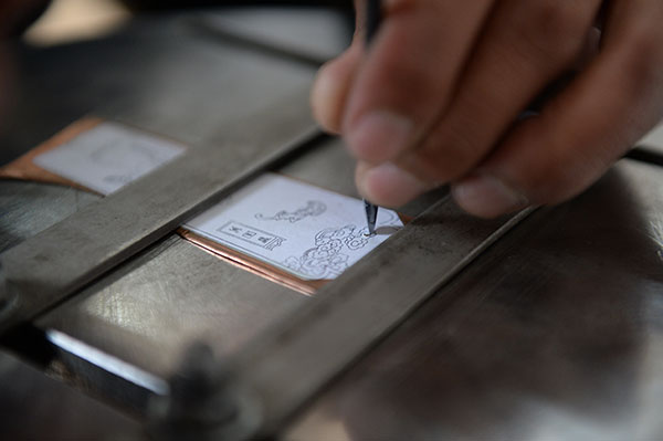 One of Jin's apprentices engraves decorations on the black copper, Nov 19, 2015. (Photo by Tan Qing/For chinadaily.com.cn) One of Jin's apprentices engraves decorations on the black copper, Nov 19, 2015. (Photo by Tan Qing/For chinadaily.com.cn)
