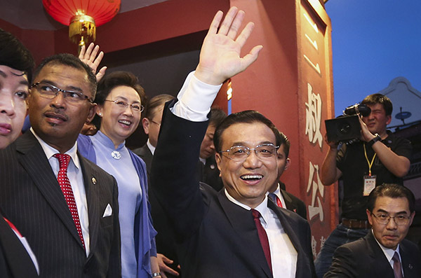Premier Li Keqiang and his wife Cheng Hong greet the public in front of a store selling specialized products during the couple's visit to Malacca on Sunday. (Photo/Xinhua)