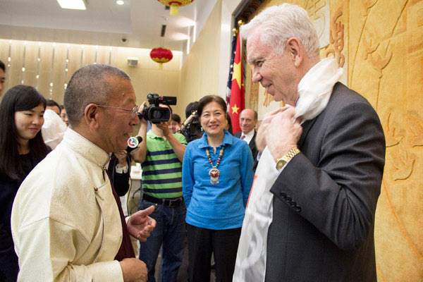 Living Buddha Shingtsa Tenzinchodrak (left) presents a Tibetan Kha Ta to US-China Partnerships Chairman Charles Foster (right) and while Foster's wife and actress Lily Chen Foster looks on. (Photo by May Zhou/China Daily)