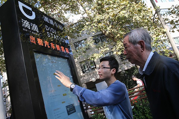 An employee of Didi Kuaidi shows a senior citizen how to book a car by using the touchscreen device at one of the many Didi stations installed by the company in Shanghai neighborhoods in October. (Photo/Xinhua) An employee of Didi Kuaidi shows a senior citizen how to book a car by using the touchscreen device at one of the many Didi stations installed by the company in Shanghai neighborhoods in October. (Photo/Xinhua)