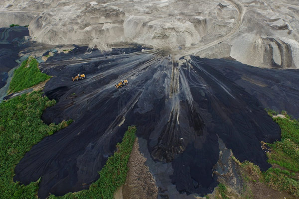 Bulldozers from a non-ferrous metal processing company spread waste residue across a mudflat in Wanwu township, Ningde, Fujian province. Last year, the mercury level in the mudflat's soil was 10 times higher than the national standard. Chen Jie/for China Daily