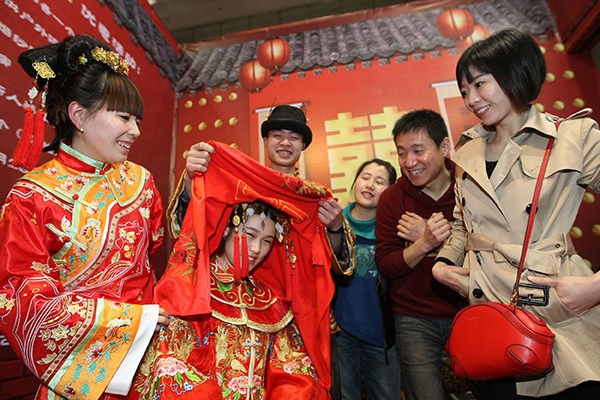 Business promotion staff dress in Chinese wedding clothes to promote folk wedding supplies during a recent wedding fair in Chongqing. (Photo provided to China Daily) Business promotion staff dress in Chinese wedding clothes to promote folk wedding supplies during a recent wedding fair in Chongqing. (Photo provided to China Daily)