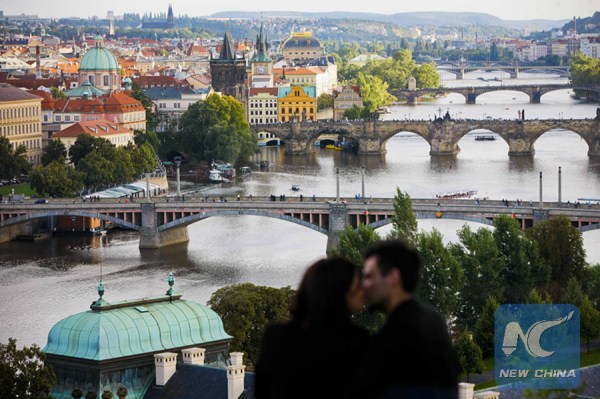 A young couple kiss with the Vltava River and the Charles Bridge in the background in Prague, capital of the Czech Republic, on Sept. 1, 2013. (Xinhua/Zhou Lei)