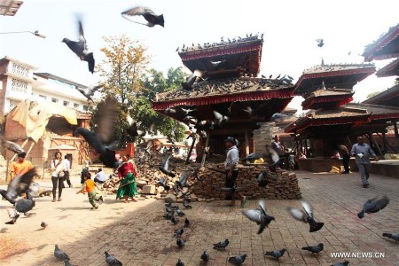 Pigeons fly as people walk past temples at the ruins of Hanumandhoka Durbar Square in Kathmandu, Nepal, April 25, 2016. Nepal is marking the first anniversary of the April 25 earthquake which killed nearly 9,000 people last year. (Photo: Xinhua/Sunil Sharma) Pigeons fly as people walk past temples at the ruins of Hanumandhoka Durbar Square in Kathmandu, Nepal, April 25, 2016. Nepal is marking the first anniversary of the April 25 earthquake which killed nearly 9,000 people last year. (Photo: Xinhua/Sunil Sharma)