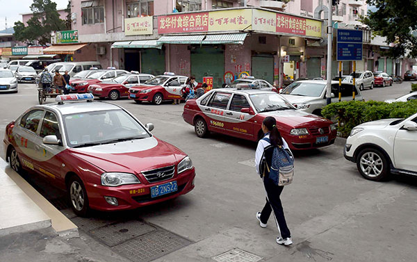 A woman walks along a street lined with taxis in Dawang village, Shenzhen, Guangdong province, in February. The village is home to many taxi drivers and their families. Zhang Wei/For China Daily A woman walks along a street lined with taxis in Dawang village, Shenzhen, Guangdong province, in February. The village is home to many taxi drivers and their families. Zhang Wei/For China Daily