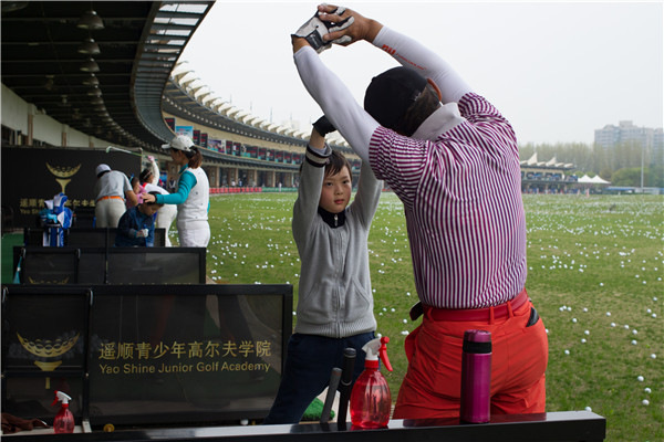 A boy practices under the guidance of a coach at the Yao Shine Golf School in Shanghai on April 9.GAO ERQIANG/CHINA DAILY A boy practices under the guidance of a coach at the Yao Shine Golf School in Shanghai on April 9.GAO ERQIANG/CHINA DAILY