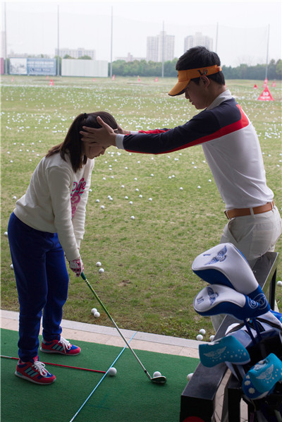 A girl practices under the guidance of a coach at the Yao Shine Golf School in Shanghai on April 9.GAO ERQIANG/CHINA DAILY A girl practices under the guidance of a coach at the Yao Shine Golf School in Shanghai on April 9.GAO ERQIANG/CHINA DAILY