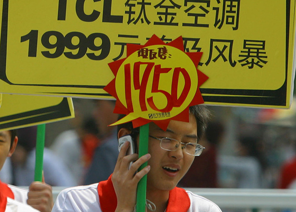 A man receives a phone call while hand-holding a billboard advertising air conditioners made by TCL Group in Nanjing. (An Xin/For China Daily)