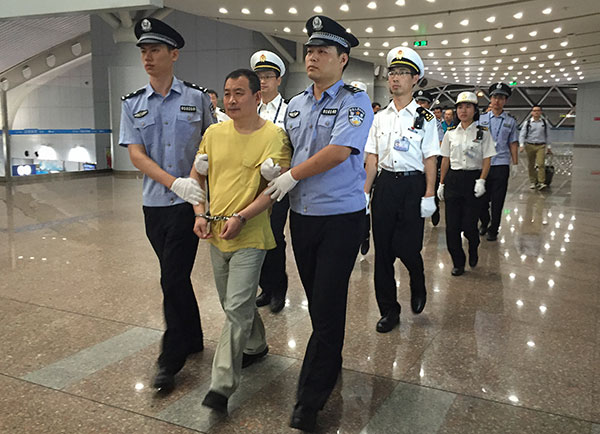 A smuggling suspect surnamed Huang is escorted back to China on Sunday after being in Peru for 18 years. CAI YANHONG/CHINA DAILY A smuggling suspect surnamed Huang is escorted back to China on Sunday after being in Peru for 18 years. CAI YANHONG/CHINA DAILY