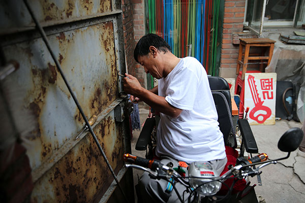 Yang Yufang fixes a lock at his home. WANG ZHUANGFEI/CHINA DAILY Yang Yufang fixes a lock at his home. WANG ZHUANGFEI/CHINA DAILY