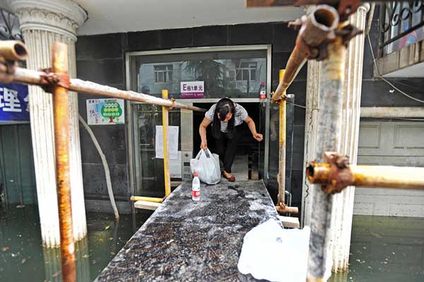 A woman walks onto part of a 2,000-meter-long long wooden platform built as a makeshift bridge at a residential community in Wuhan on July 11, 2016. Rising waters inundated the city and the flooding inconvenienced residents. (Photo/youth.cn) A woman walks onto part of a 2,000-meter-long long wooden platform built as a makeshift bridge at a residential community in Wuhan on July 11, 2016. Rising waters inundated the city and the flooding inconvenienced residents. (Photo/youth.cn)