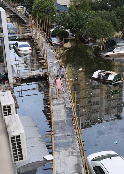 People walk on a 2,000-meter-long wooden platform built as a makeshift bridge at a residential community in Wuhan on July 11, 2016. Rising waters inundated the city and the flooding inconvenienced residents. (Photo/youth.cn) People walk on a 2,000-meter-long wooden platform built as a makeshift bridge at a residential community in Wuhan on July 11, 2016. Rising waters inundated the city and the flooding inconvenienced residents. (Photo/youth.cn)