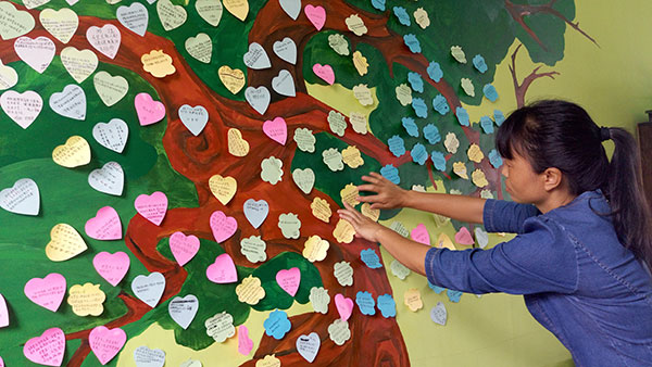 A teacher at Yingjiang No 3 High School posts students' love messages in the school's Youth Love Station on June 22. YANG WANLI/CHINA DAILY A teacher at Yingjiang No 3 High School posts students' love messages in the school's Youth Love Station on June 22. YANG WANLI/CHINA DAILY