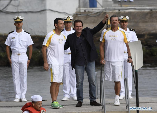 Rio de Janeiro's mayor Eduardo Paes shows the Olympic flame in a lantern in Rio de Janeiro, Brazil, on Aug. 3, 2016. The Olympic torch arrives in Rio de Janeiro on Wednesday. (Photo/Xinhua)