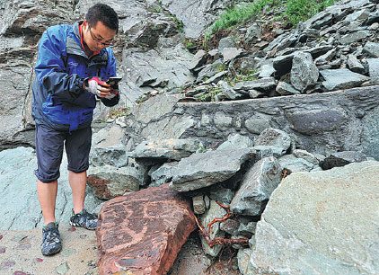 A staff member at the Helan Mountain Rock Paintings Conservation Park in the Ningxia Hui autonomous region checks rock carvings damaged by flooding this week. Wu Xiaoyu / For China Daily A staff member at the Helan Mountain Rock Paintings Conservation Park in the Ningxia Hui autonomous region checks rock carvings damaged by flooding this week. Wu Xiaoyu / For China Daily