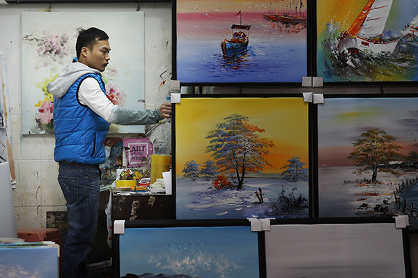 A worker arranges oil paintings at an art gallery in Dafen. (Photo by Xu Yuanchang/China Daily) A worker arranges oil paintings at an art gallery in Dafen. (Photo by Xu Yuanchang/China Daily)