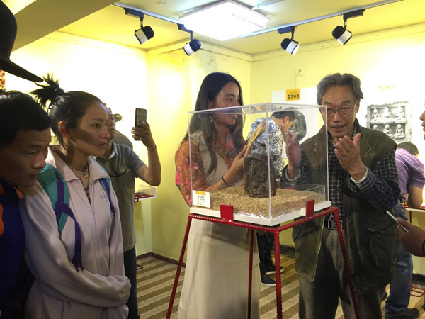 Yu Youxin, a prominent artist, briefs visitors about a tsa-tsa, or miniature figurine, exhibited on Barkor Street in Lhasa, Tibet autonomous region, August 14, 2016.(Photo by Palden Nyima/chinadaily.com.cn) Yu Youxin, a prominent artist, briefs visitors about a tsa-tsa, or miniature figurine, exhibited on Barkor Street in Lhasa, Tibet autonomous region, August 14, 2016.(Photo by Palden Nyima/chinadaily.com.cn)