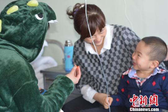 A volunteer dressed up as a dinosaur cheers up a boy. (Photo/chinanews.com) A volunteer dressed up as a dinosaur cheers up a boy. (Photo/chinanews.com)