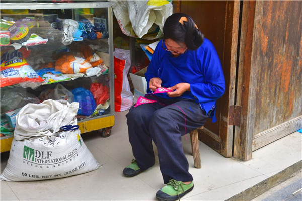 A senior local does the traditional sewing work at her shop. (Photo by Zhang Xingjian/chinadaily.com.cn) A senior local does the traditional sewing work at her shop. (Photo by Zhang Xingjian/chinadaily.com.cn)