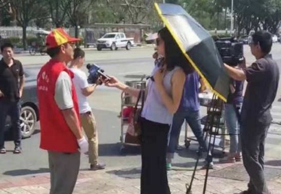 A female reporter holds an umbrella while reporting on disaster relief A female reporter holds an umbrella while reporting on disaster relief