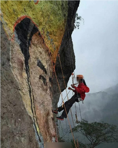 A woman climbs on a cliff to make a portrait painting for the man she loves. (Photo/Qianjiang Evening News) A woman climbs on a cliff to make a portrait painting for the man she loves. (Photo/Qianjiang Evening News)