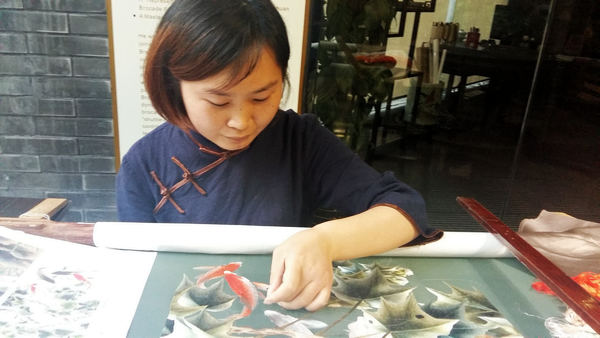 Jiang Mei shows off her skills of Shu embroidery with a piece featuring fish and flowers at the Chengdu Shu Brocade and Embroidery Museum. (Photo by Huang Zhiling/China Daily) Jiang Mei shows off her skills of Shu embroidery with a piece featuring fish and flowers at the Chengdu Shu Brocade and Embroidery Museum. (Photo by Huang Zhiling/China Daily)